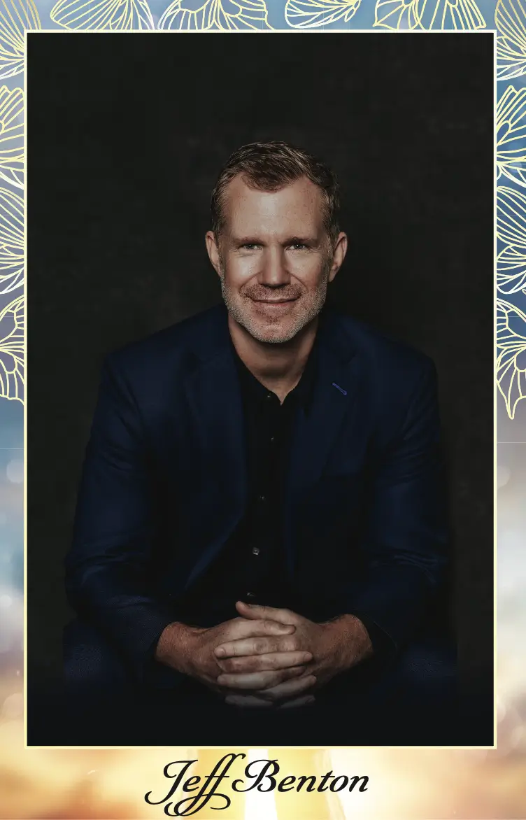 Smiling man in business attire with dark background.