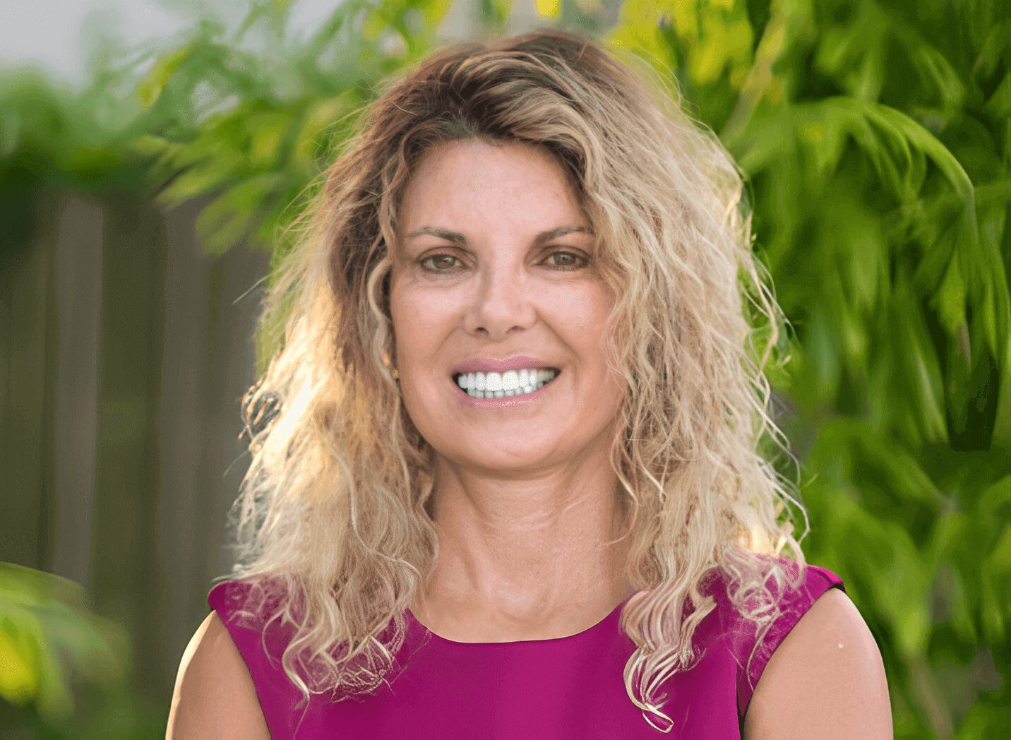 Close-up portrait of smiling woman in magenta
